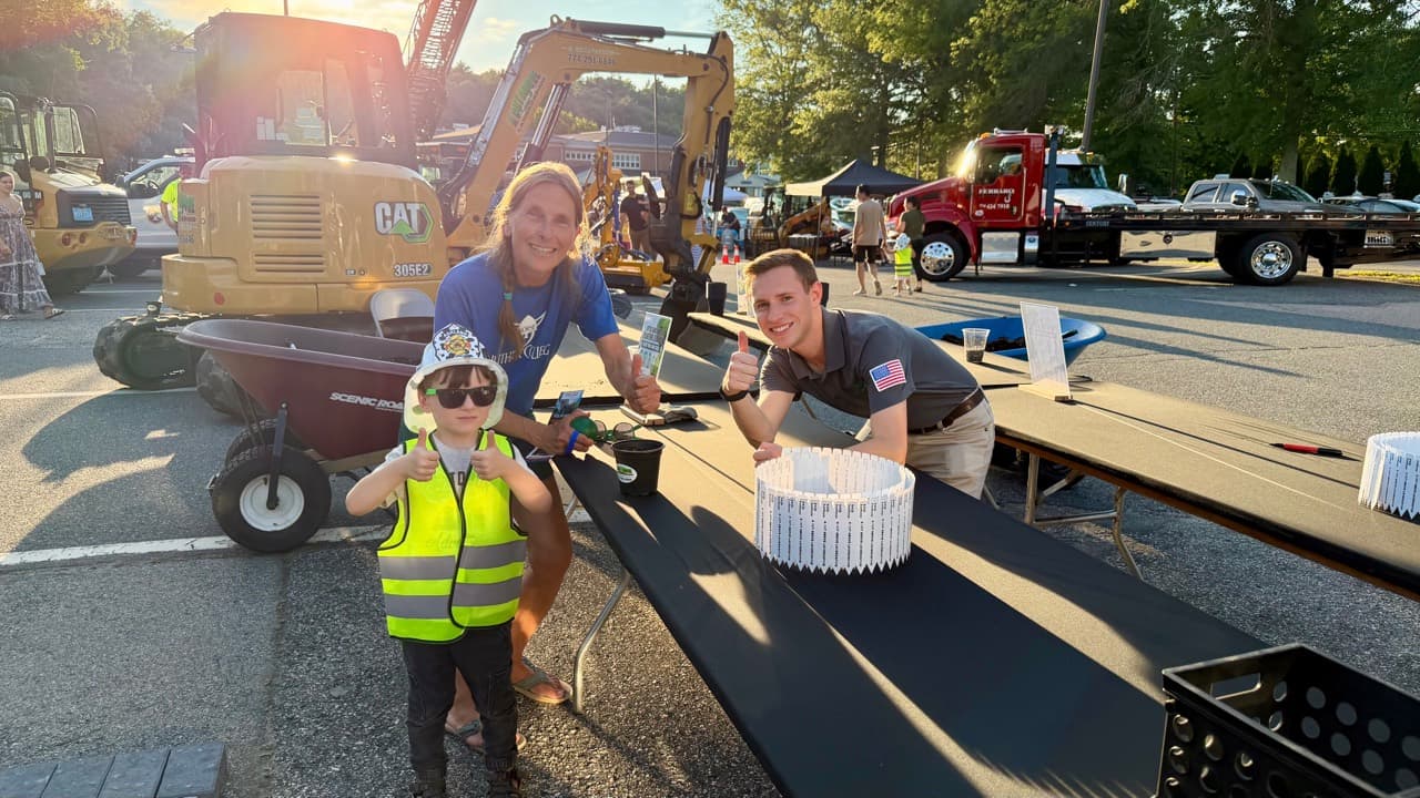 A young gardener and community volunteers giving a thumbs-up beside the Ashland sunflower planting station