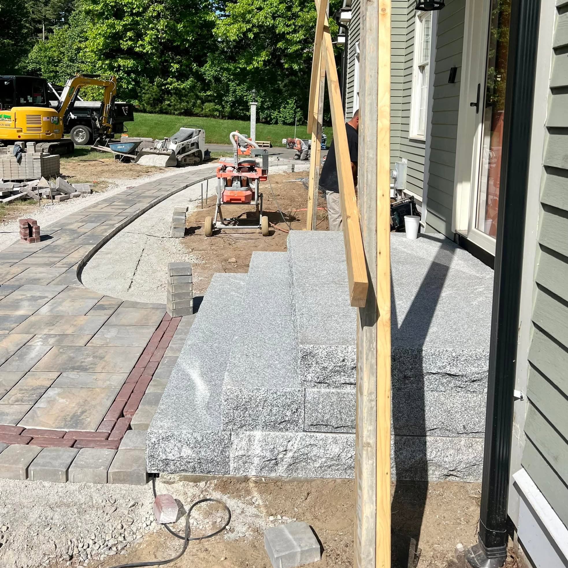 Paver walkway installation in progress with base preparation and compact equipment