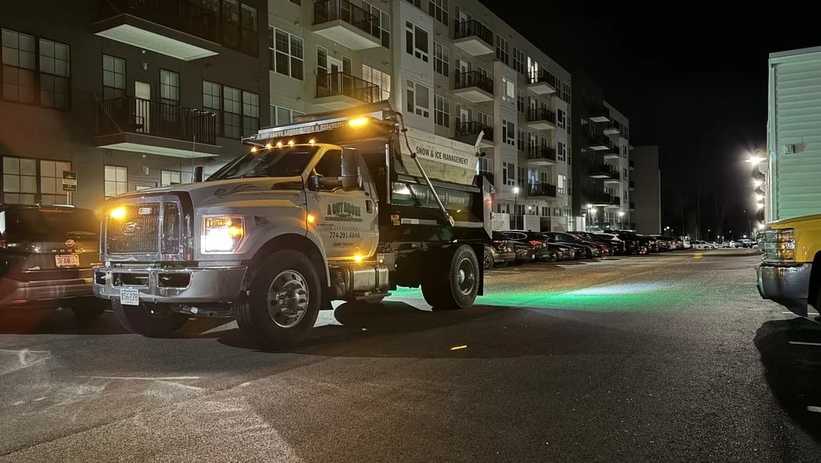 A Cut Above truck equipped with a salt spreader at an apartment property at night