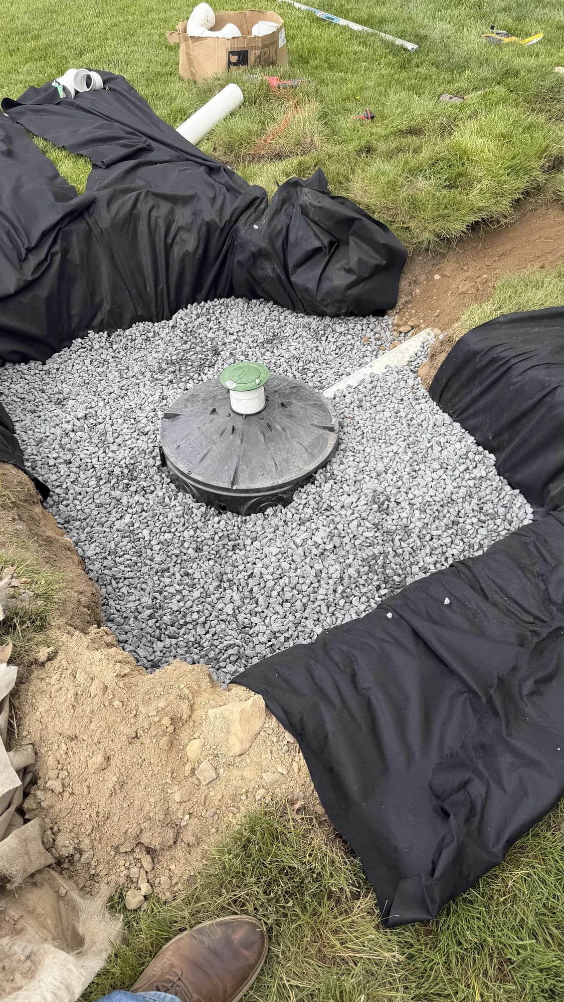 Drainage structure and pipe installed in crushed stone within a fabric-lined excavation