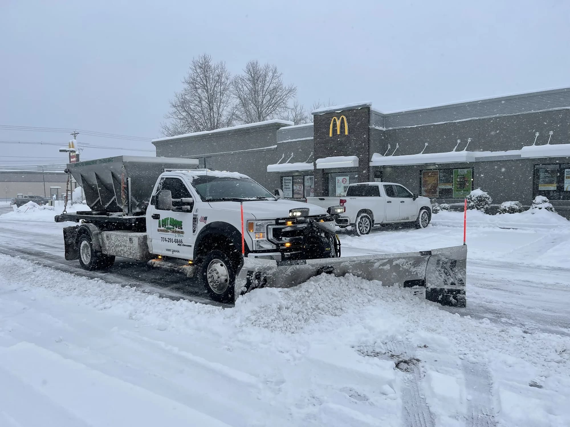 A Cut Above plow truck clearing snow from a restaurant parking lot during the day