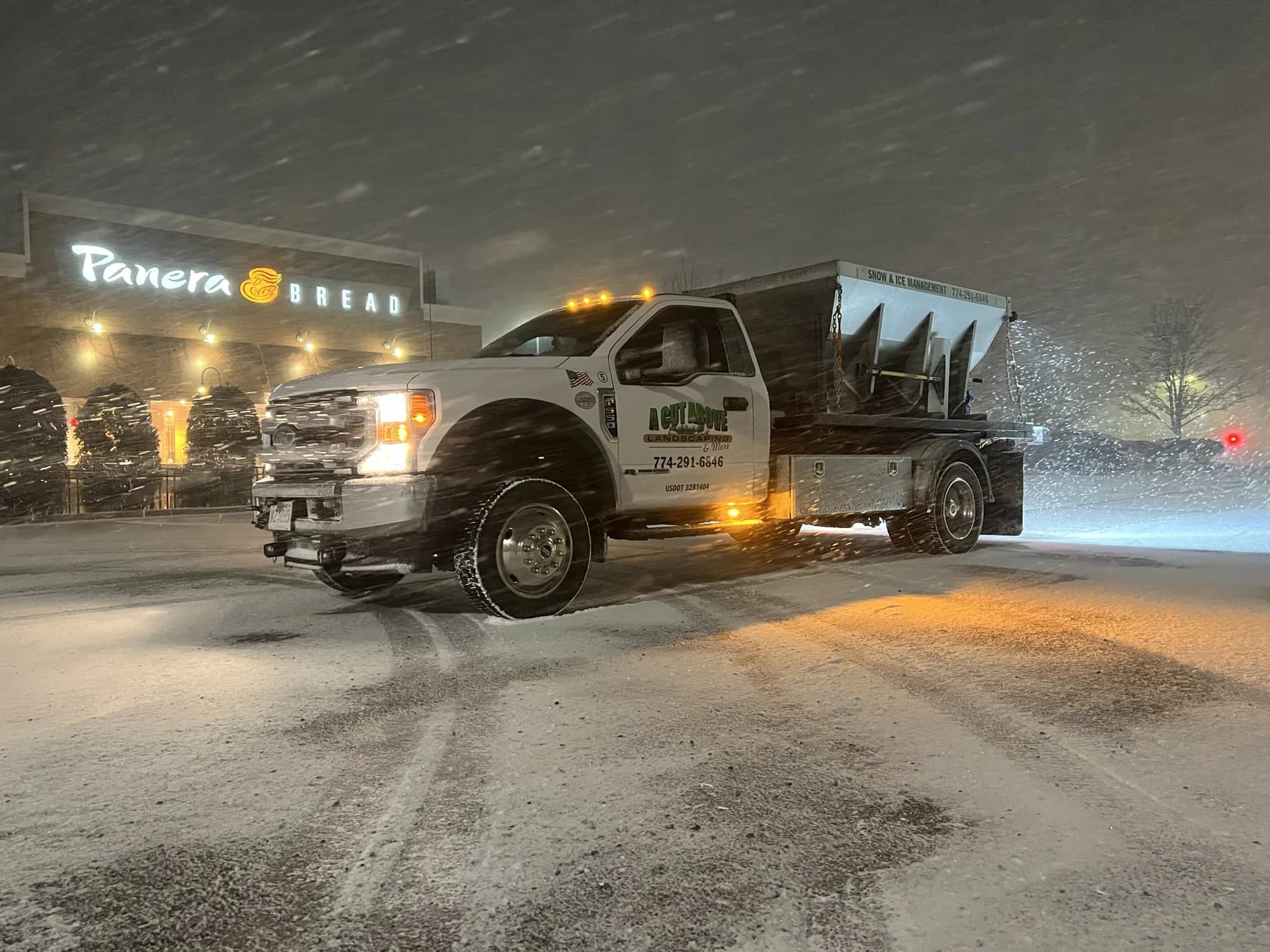 A Cut Above winter-service truck with a salt spreader at a retail property during snowfall