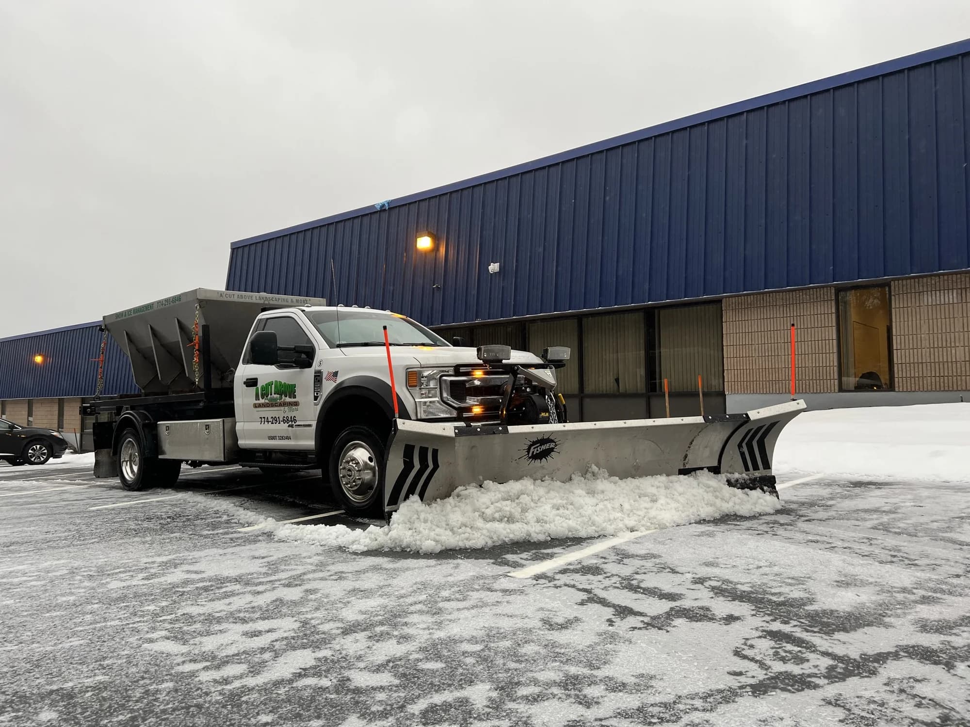 A Cut Above plow truck clearing snow beside a commercial warehouse
