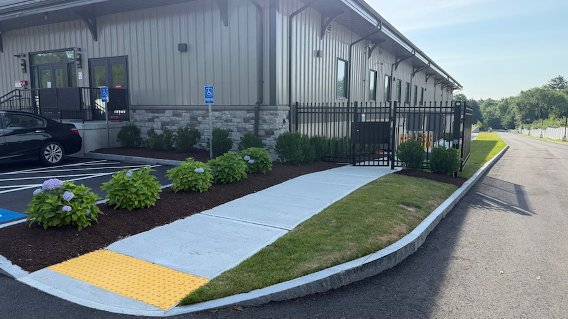 Completed commercial entrance with an accessible walkway, lawn, and planting beds