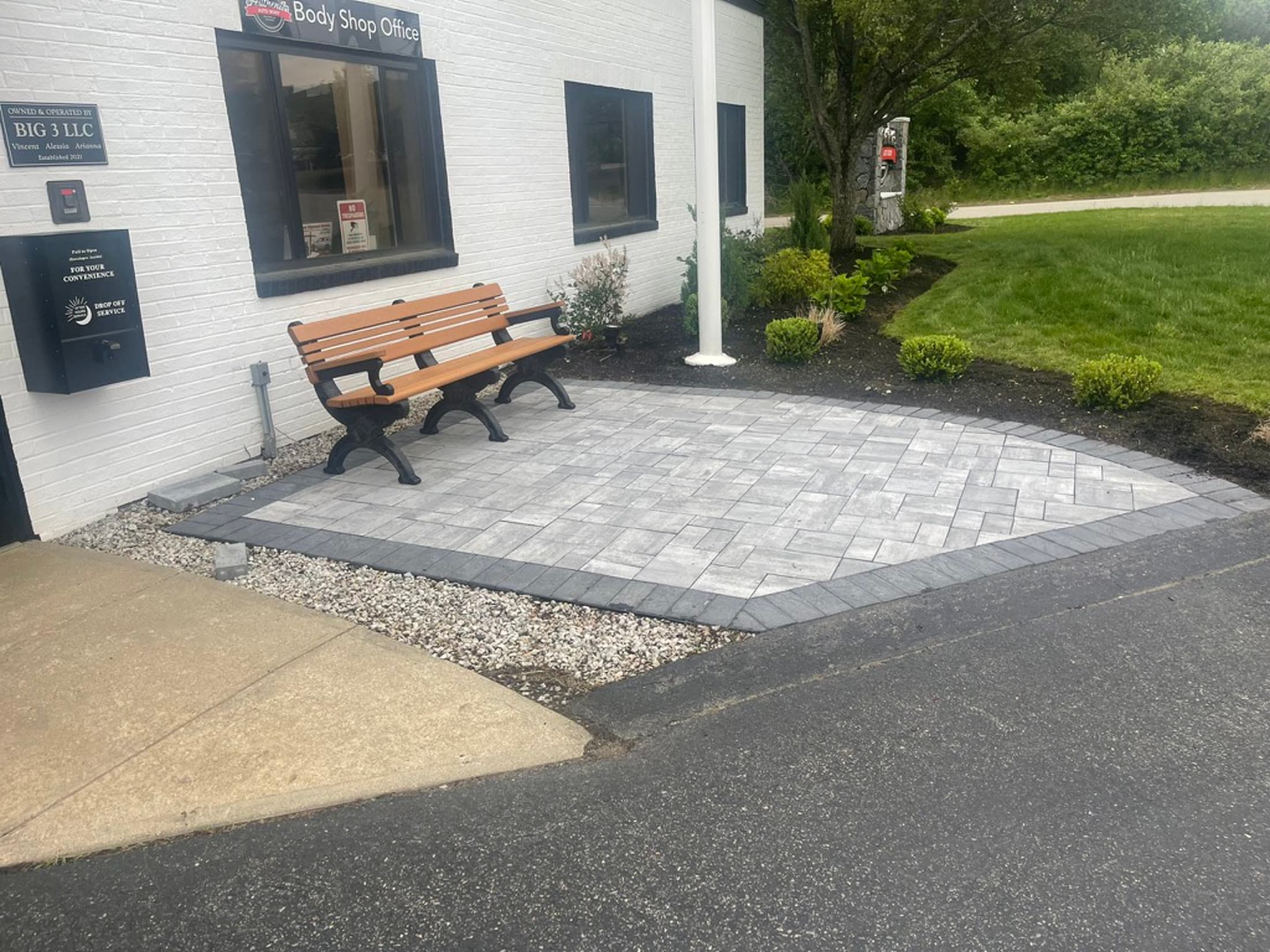 Completed commercial paver entrance with a bench and landscaped border