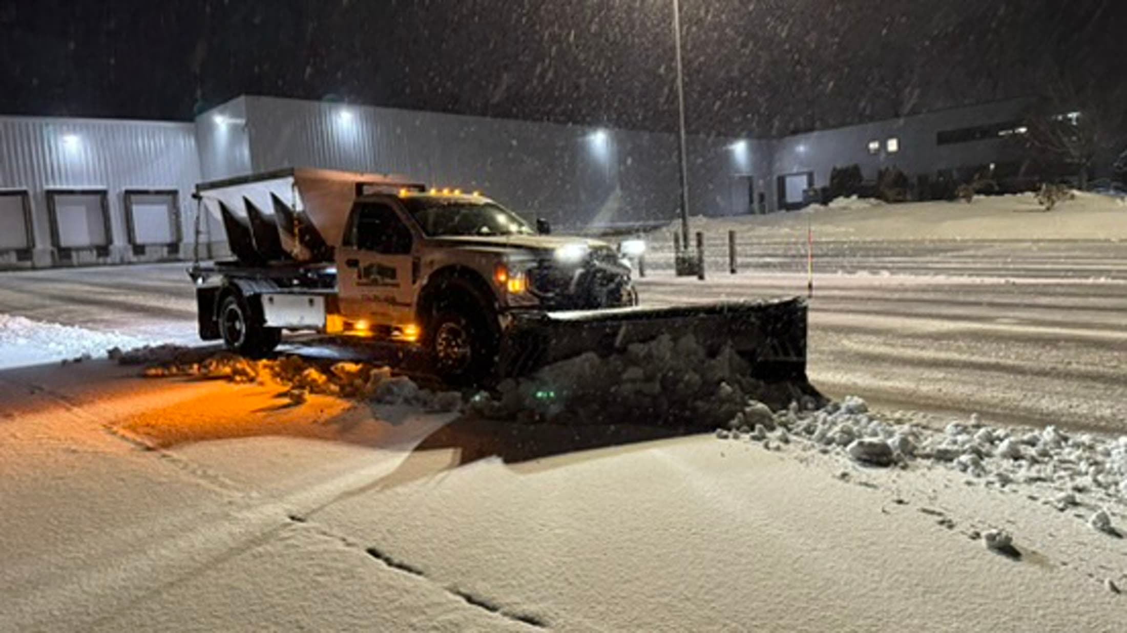Plow truck actively clearing snow from a commercial service area