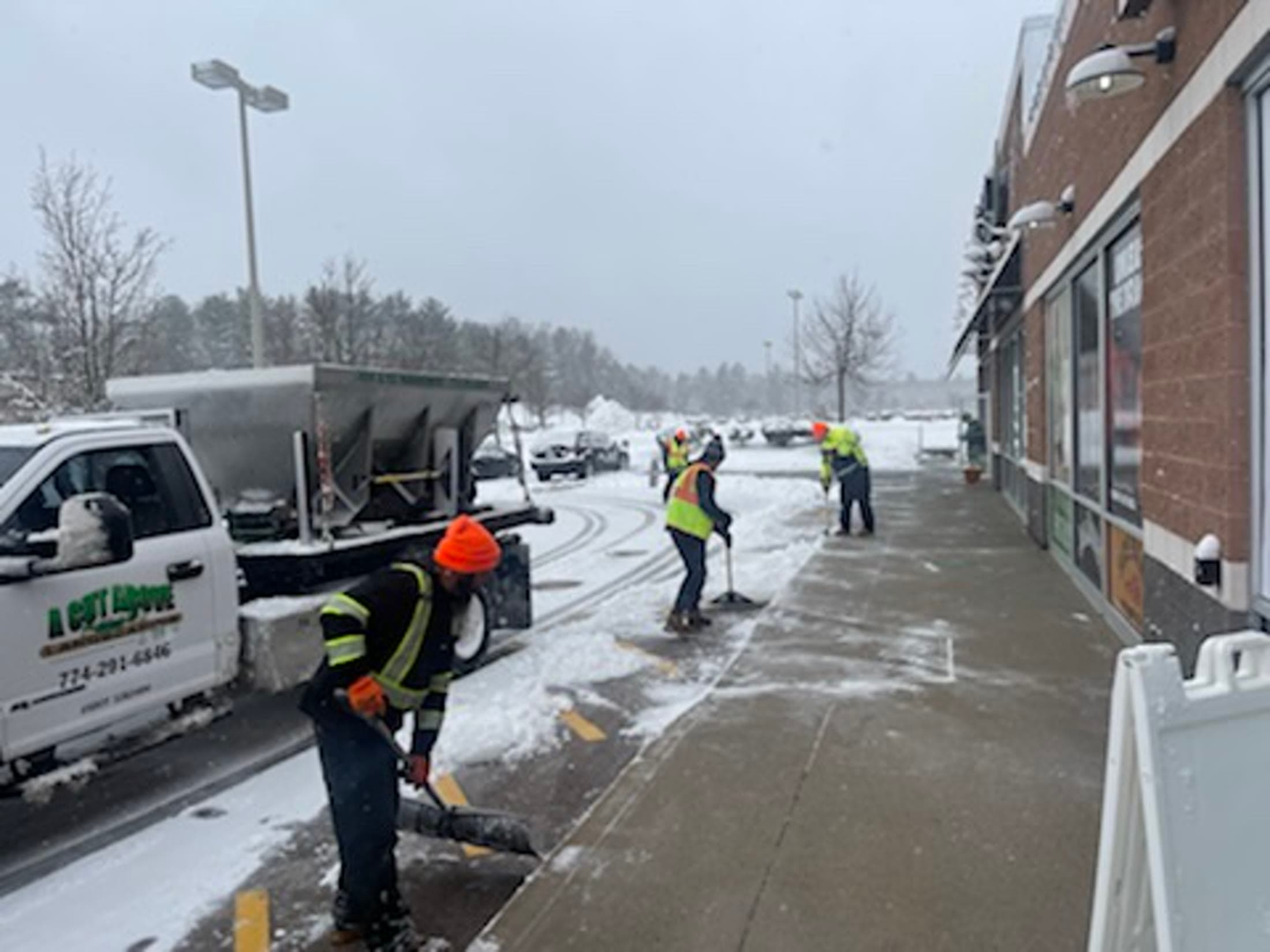 Crew clearing snow from a commercial walkway and entrance