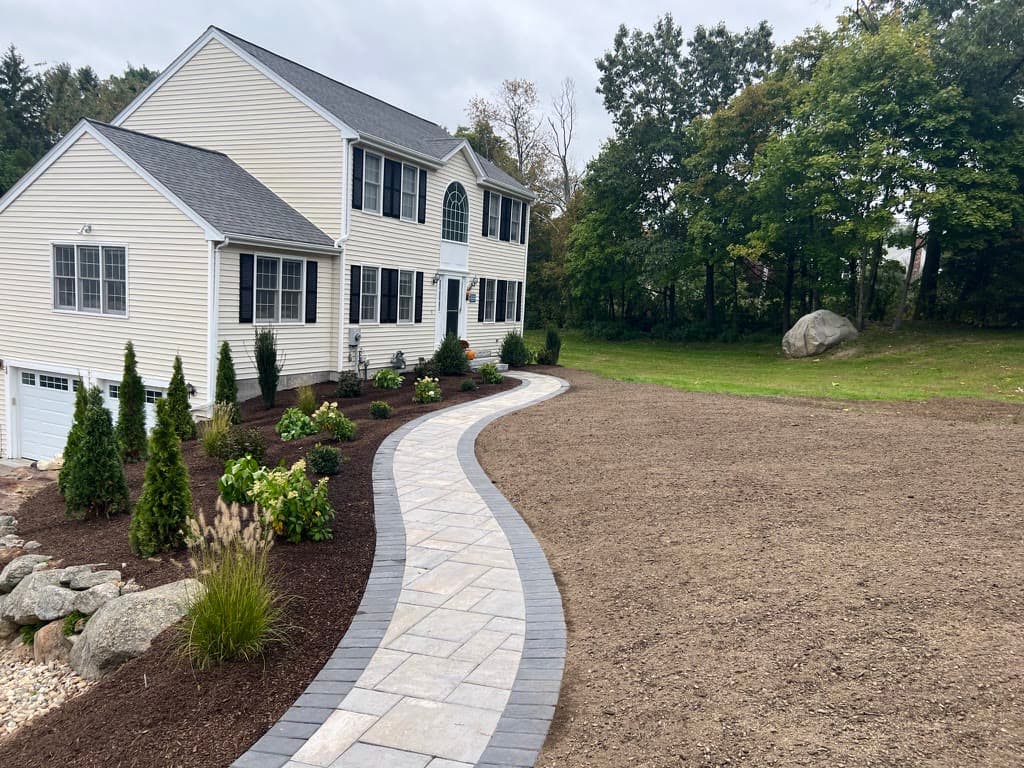 Sweeping curved paver walkway through a newly finished landscape