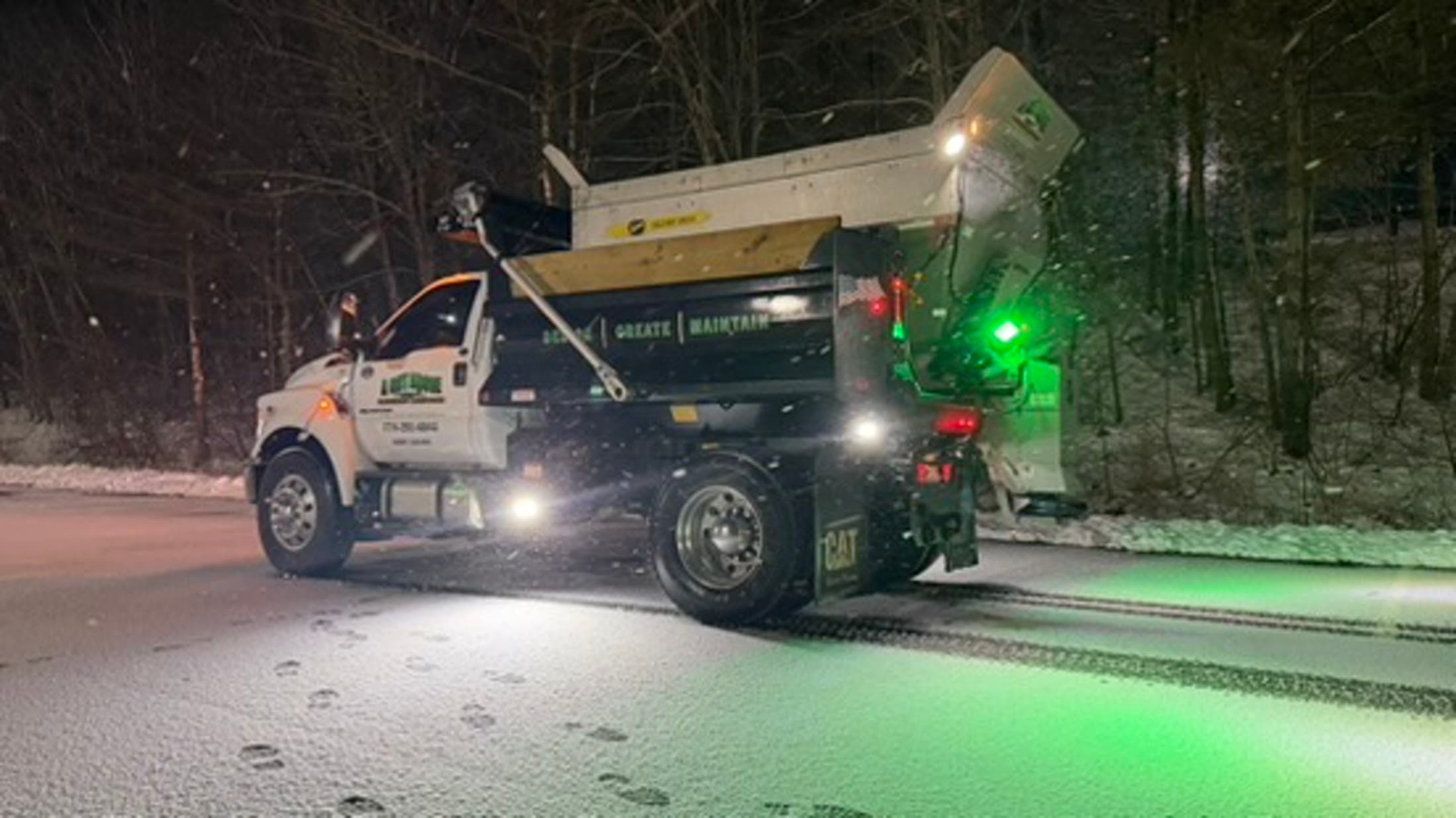 Deicing truck treating a commercial parking area at night