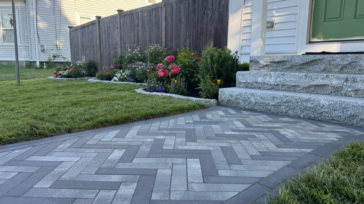 Granite entry steps with a herringbone paver landing and landscaped beds