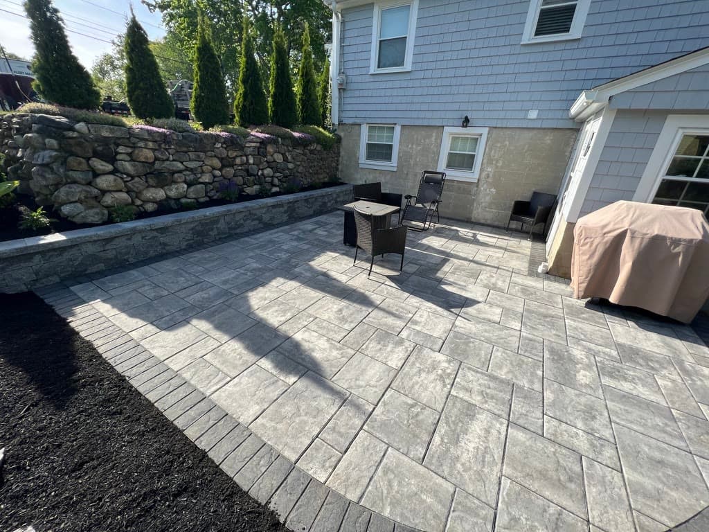 Finished paver patio with a low seating wall and natural stone retaining wall