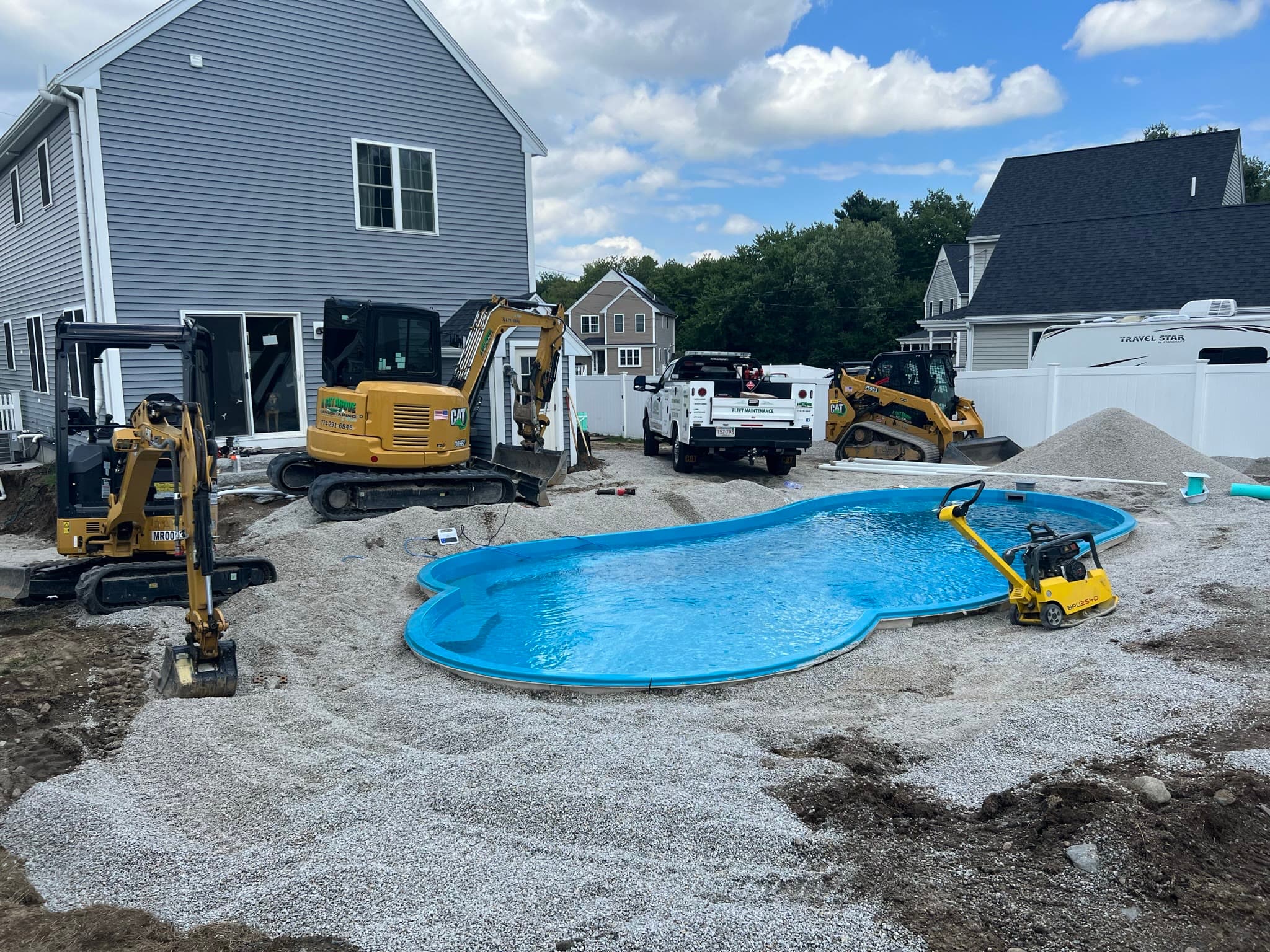 Compact excavation equipment preparing the stone base around a residential pool