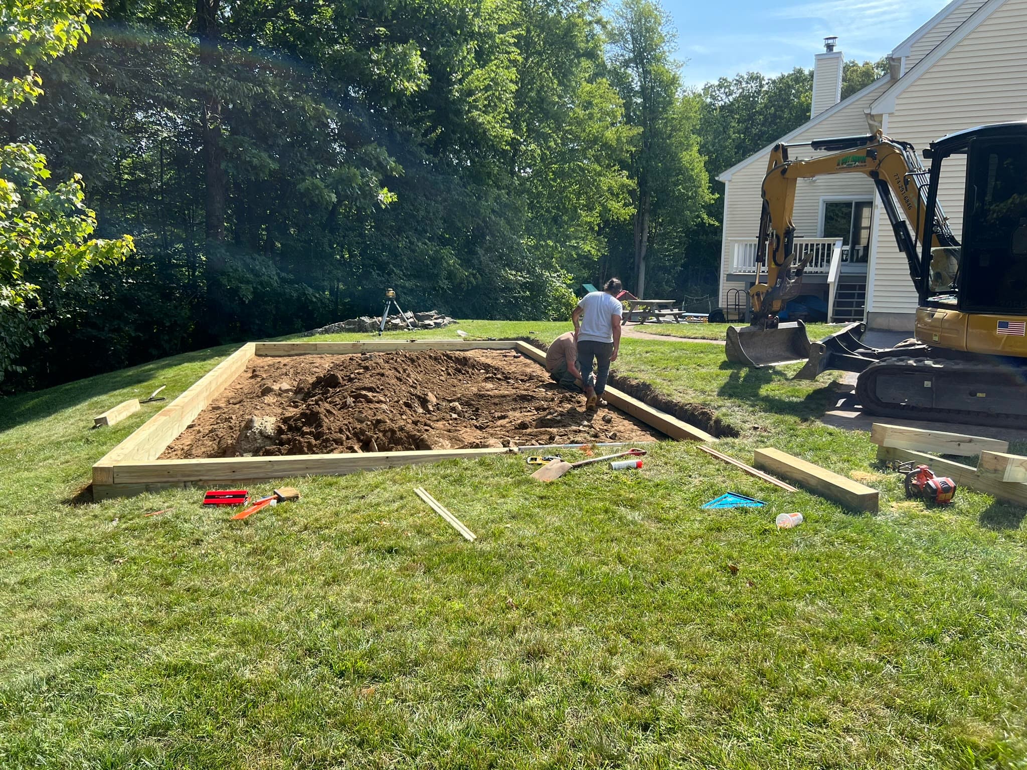 Crew and excavator preparing a framed residential pad