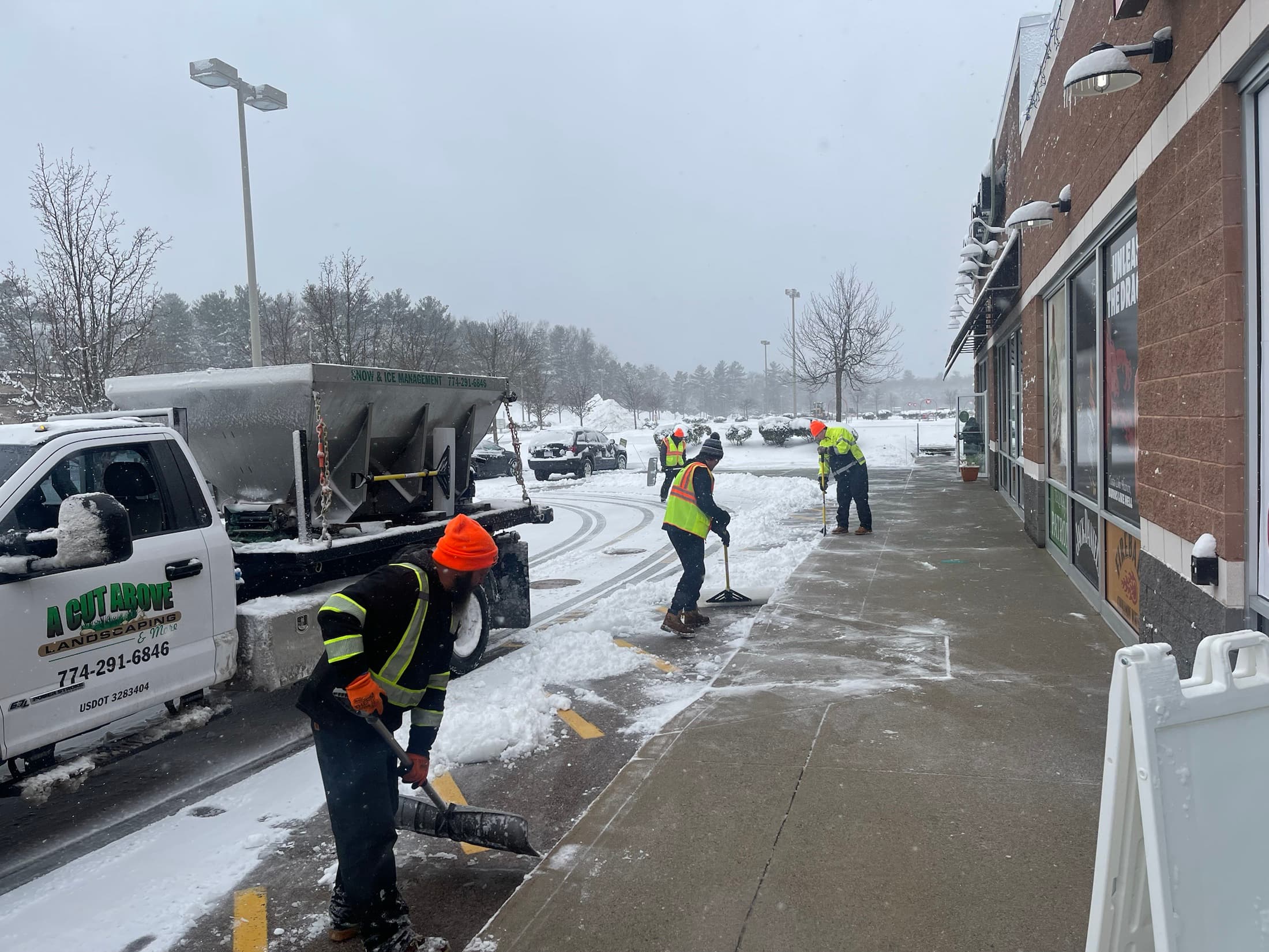 A Cut Above crew shoveling a commercial walkway during active snowfall