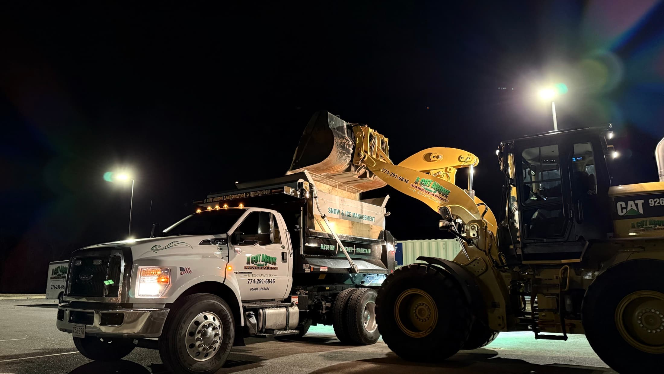 Wheel loader transferring snow into an A Cut Above dump truck at night