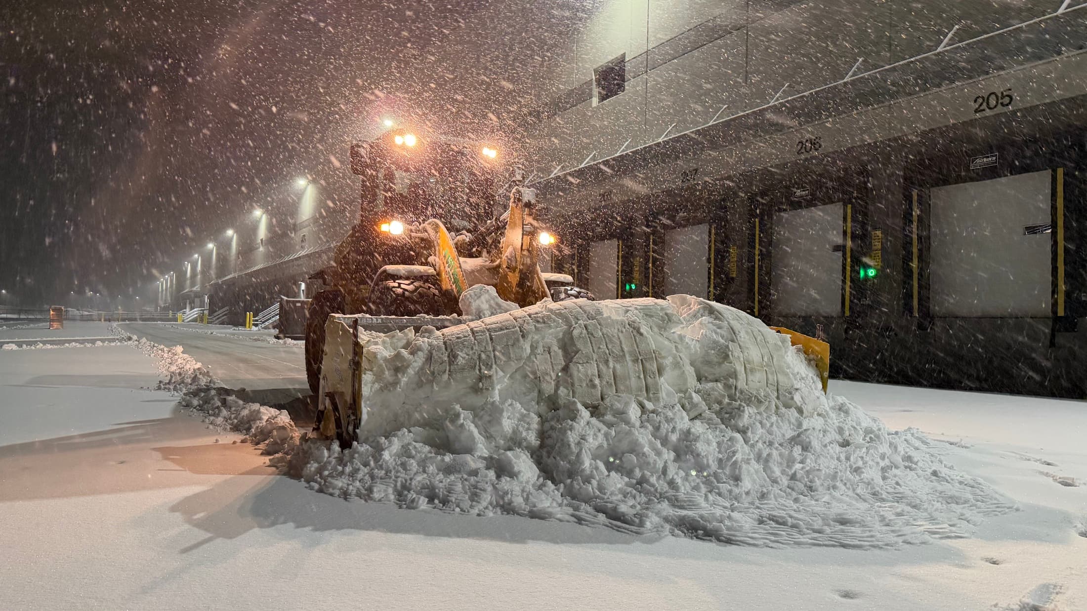Wheel loader pushing deep snow away from commercial loading docks during a storm