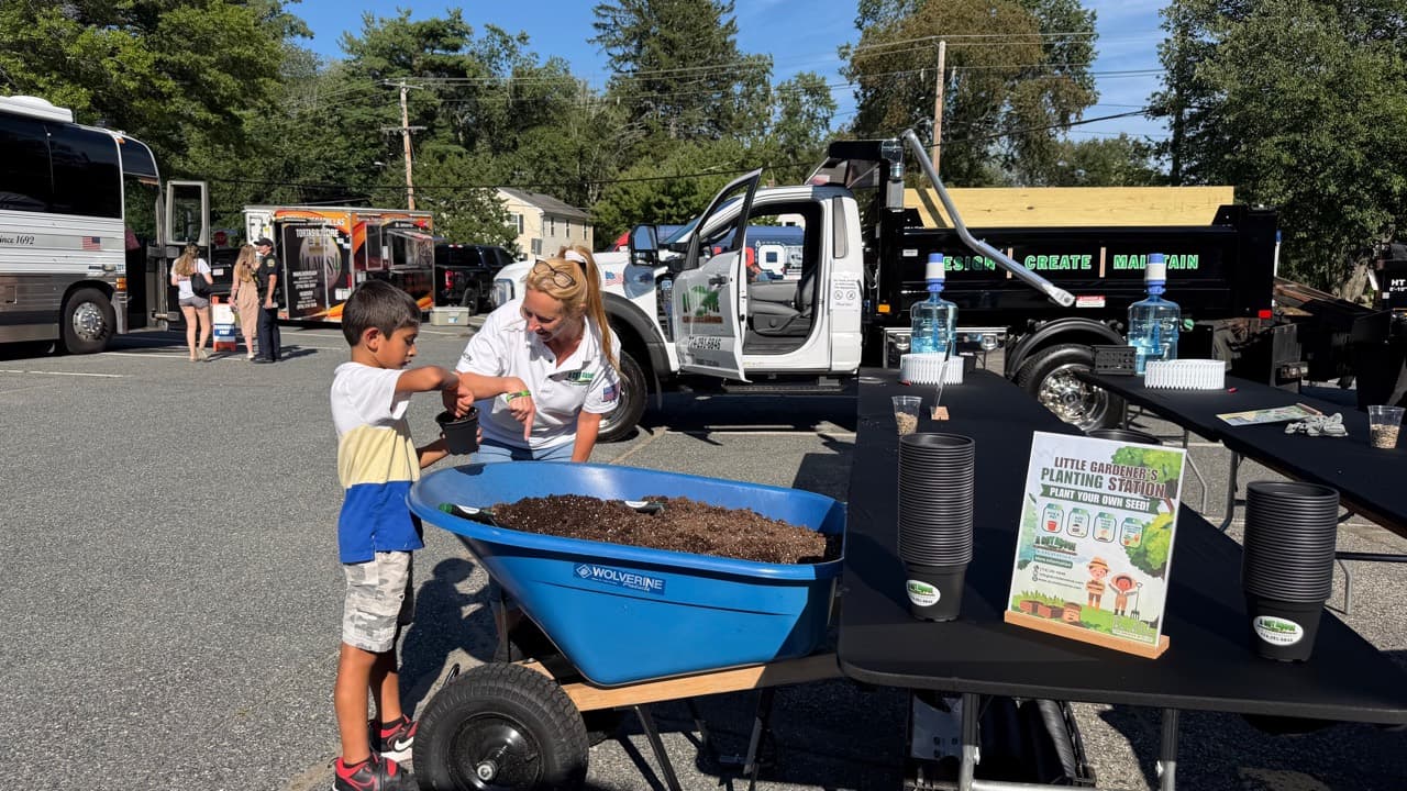 A child planting sunflower seeds at the A Cut Above Little Gardener's station during Ashland Community Safety Night Out
