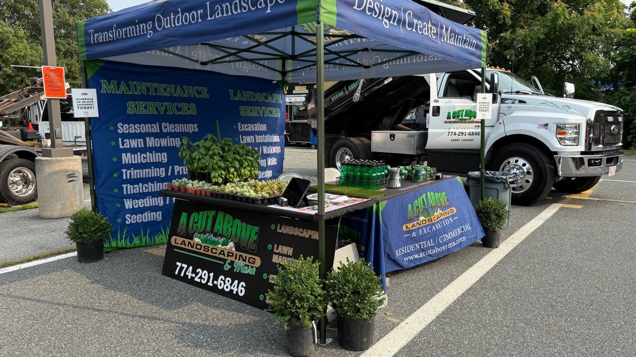 A Cut Above Ashland community event booth with plants, giveaways, and a company truck