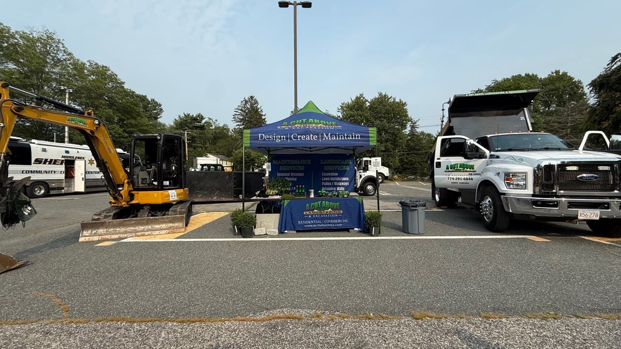 A Cut Above excavator, community booth, and dump truck at the Ashland community gathering