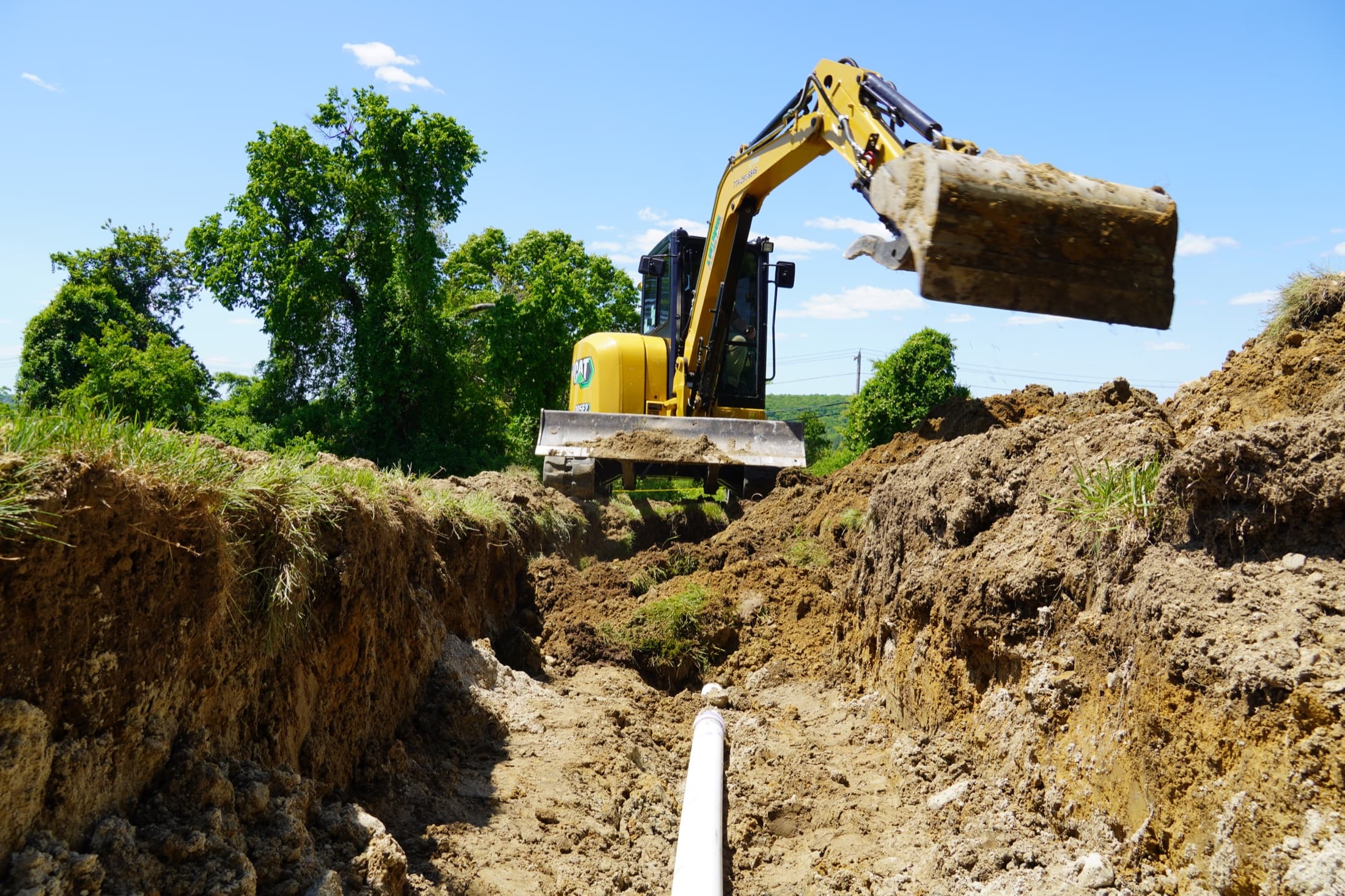 Excavator completing trench and utility preparation on an active site